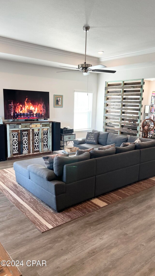 living room featuring ceiling fan, wood-type flooring, and ornamental molding