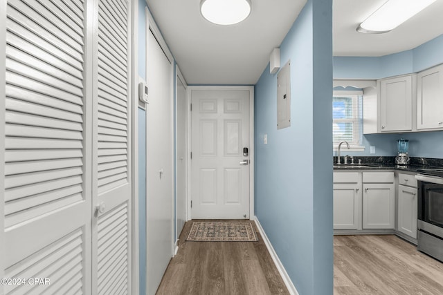 hallway featuring sink, electric panel, and light hardwood / wood-style flooring