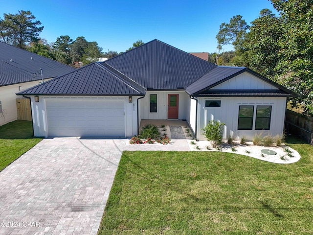 modern farmhouse with a garage, metal roof, a front lawn, and decorative driveway