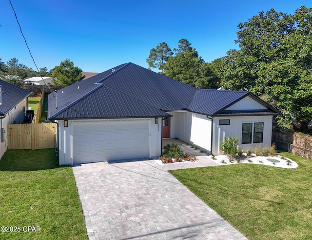 view of front of house with a garage, decorative driveway, metal roof, and fence