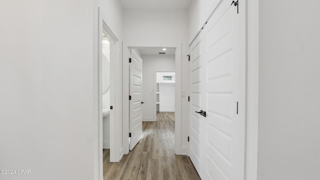 corridor with a barn door and wood-type flooring