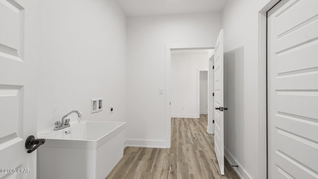 laundry area featuring electric dryer hookup, hookup for a washing machine, and light wood-type flooring