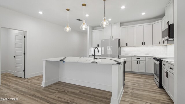 kitchen featuring white cabinets, light hardwood / wood-style flooring, an island with sink, and stainless steel appliances