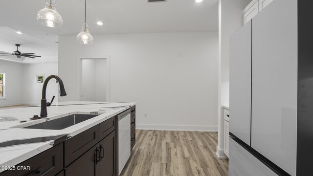 kitchen featuring pendant lighting, sink, ceiling fan, light hardwood / wood-style floors, and light stone counters