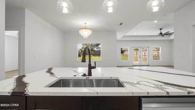 kitchen featuring decorative light fixtures, light stone countertops, and sink