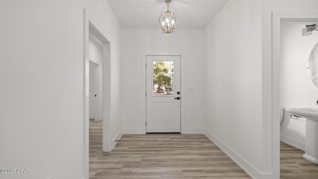 doorway to outside featuring an inviting chandelier and light hardwood / wood-style flooring