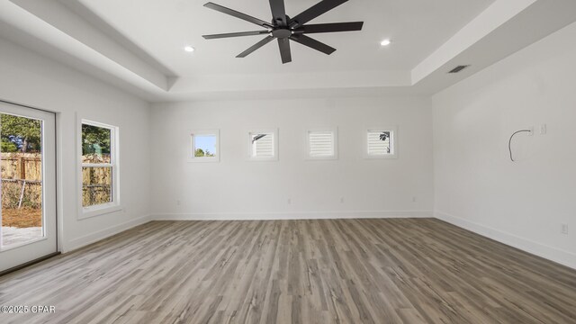 unfurnished room with a tray ceiling, ceiling fan, and light hardwood / wood-style floors