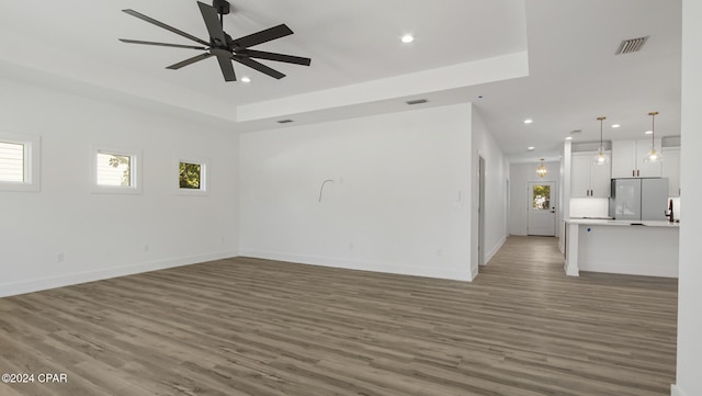 unfurnished living room featuring ceiling fan and dark wood-type flooring