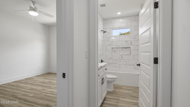 full bathroom with hardwood / wood-style floors, vanity, toilet, and tiled shower / bath