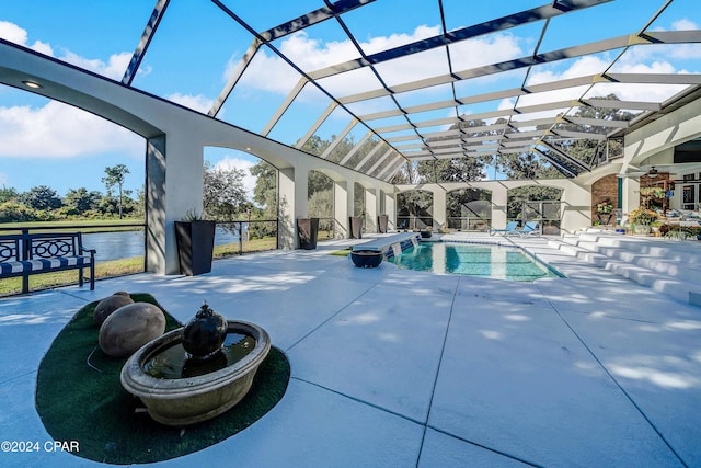 view of swimming pool featuring glass enclosure, a patio area, and a water view