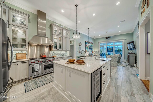 kitchen with pendant lighting, sink, stainless steel refrigerator, an island with sink, and ventilation hood