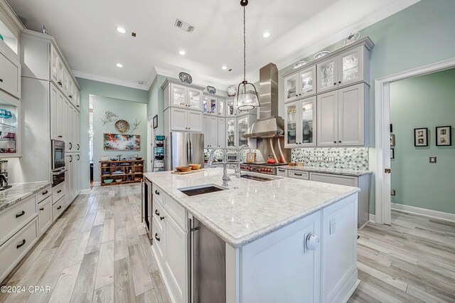 kitchen featuring stainless steel appliances, decorative backsplash, pendant lighting, wall chimney exhaust hood, and light stone counters