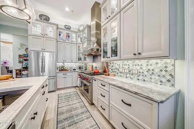 kitchen featuring tasteful backsplash, double oven range, light stone counters, and white cabinetry