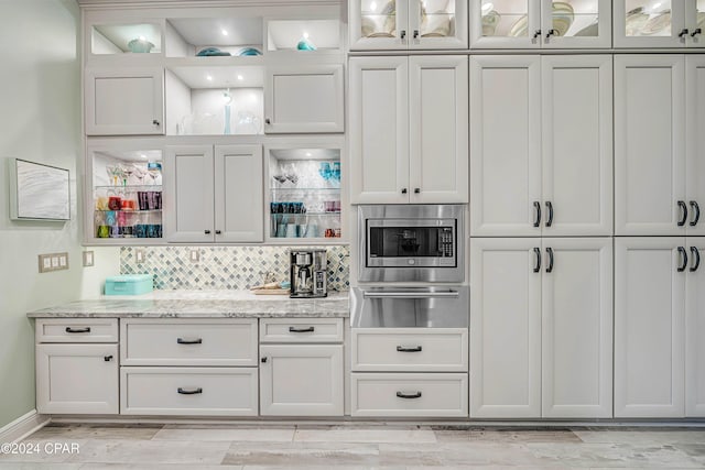 interior space with light stone counters, white cabinets, and stainless steel microwave