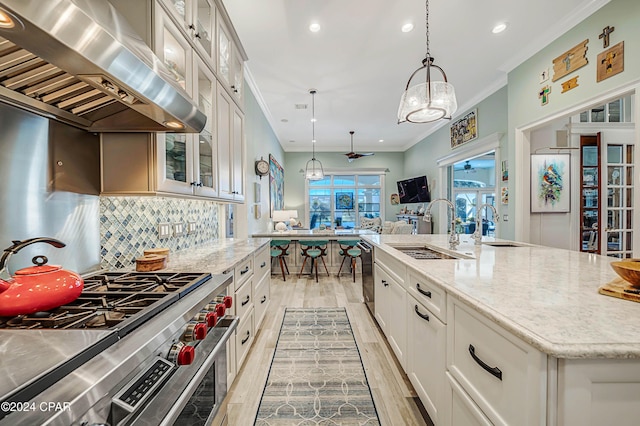 kitchen featuring white cabinetry, stainless steel stove, an island with sink, pendant lighting, and island exhaust hood