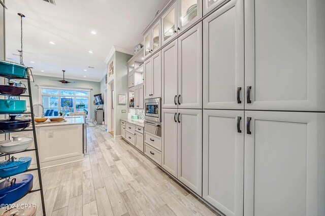 kitchen with decorative light fixtures, a breakfast bar, kitchen peninsula, light wood-type flooring, and ornamental molding