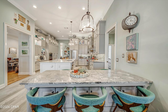 kitchen with gray cabinets, pendant lighting, tasteful backsplash, a center island, and crown molding