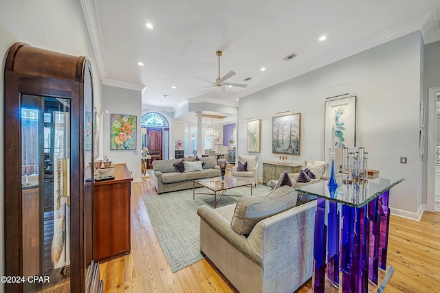 living room with ornamental molding, ceiling fan, and light wood-type flooring