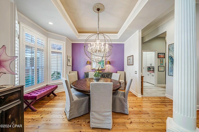 dining space featuring a tray ceiling, light hardwood / wood-style flooring, ornamental molding, and an inviting chandelier