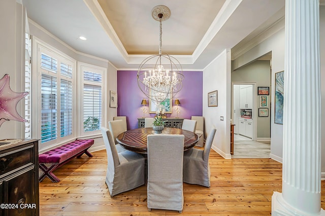 dining space with crown molding, a raised ceiling, a chandelier, and light wood-type flooring