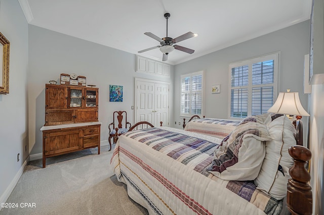 bedroom featuring ceiling fan, crown molding, a closet, and light carpet