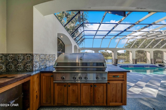 view of patio featuring glass enclosure and area for grilling