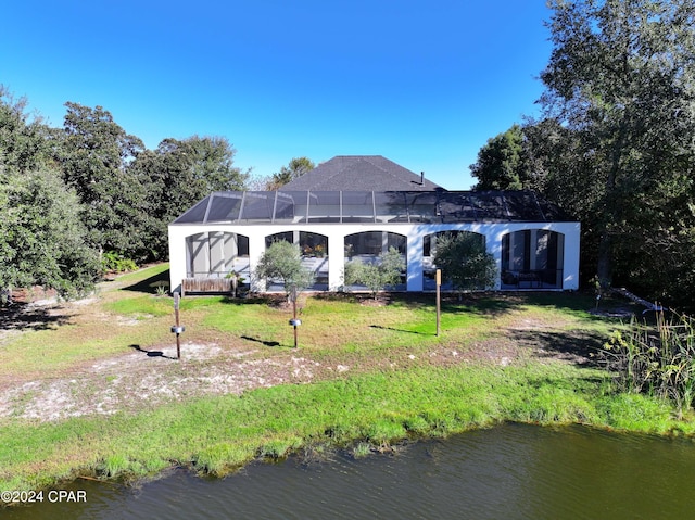 back of property with a yard, a lanai, and a water view