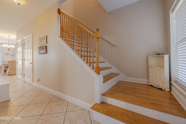 staircase with a chandelier, a healthy amount of sunlight, and wood-type flooring