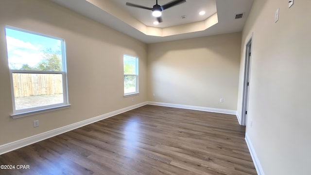 empty room featuring hardwood / wood-style floors, ceiling fan, and a raised ceiling