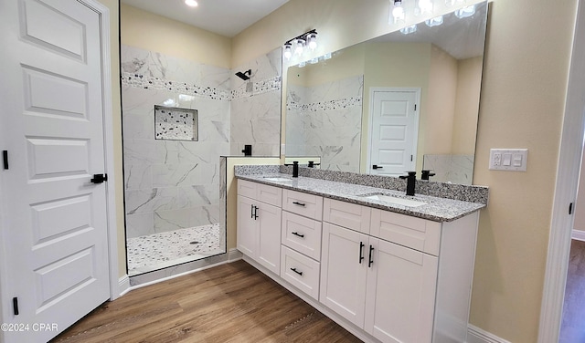 bathroom featuring a tile shower, vanity, and wood-type flooring