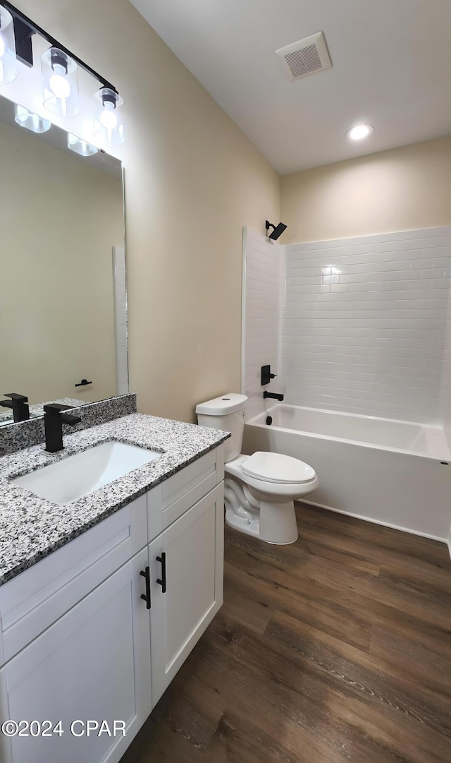 full bathroom featuring vanity, hardwood / wood-style flooring, toilet, and tiled shower / bath combo