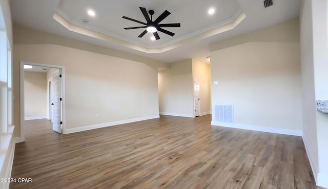 spare room featuring a raised ceiling, ceiling fan, light hardwood / wood-style floors, and ornamental molding