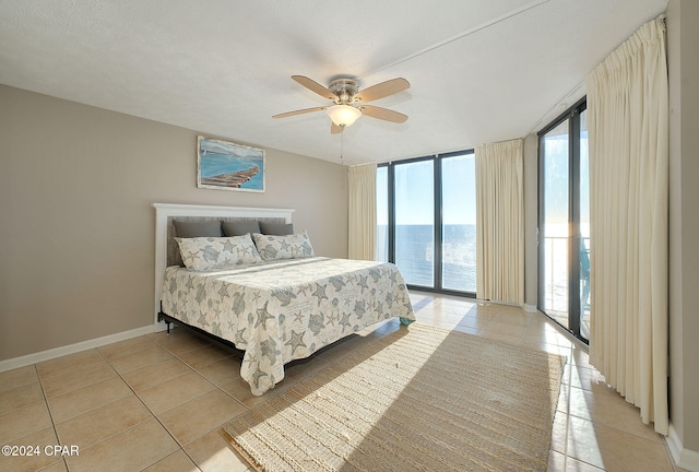 bedroom featuring access to outside, a water view, ceiling fan, light tile patterned floors, and a textured ceiling