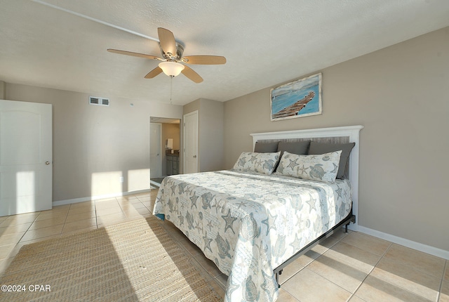 bedroom featuring ceiling fan, light tile patterned floors, and a textured ceiling