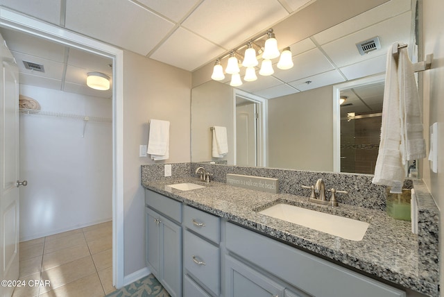 bathroom with a paneled ceiling, tile patterned flooring, vanity, and walk in shower