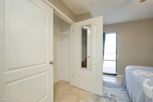 bedroom with ceiling fan, light tile patterned floors, and a closet