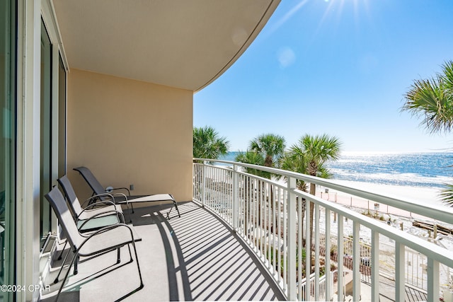 balcony with a water view and a view of the beach