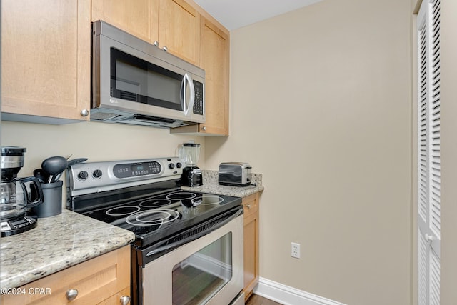 kitchen with appliances with stainless steel finishes, light brown cabinetry, and light stone countertops