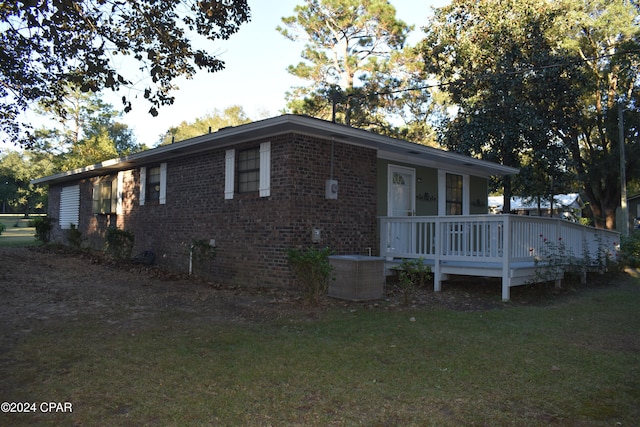 view of front of property featuring a deck, a front yard, and central air condition unit