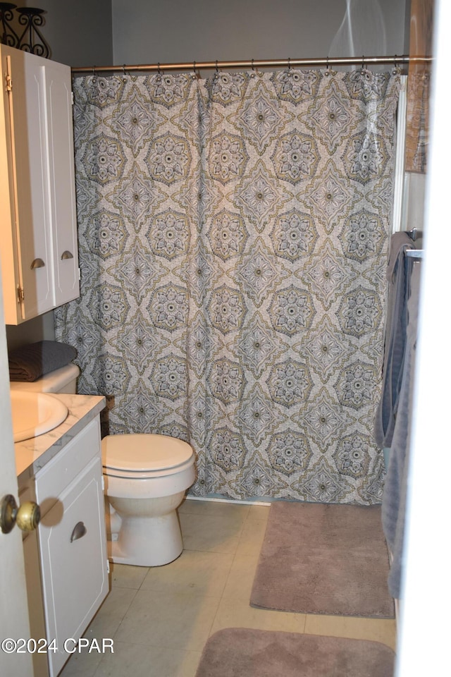 bathroom with toilet, vanity, and tile patterned floors