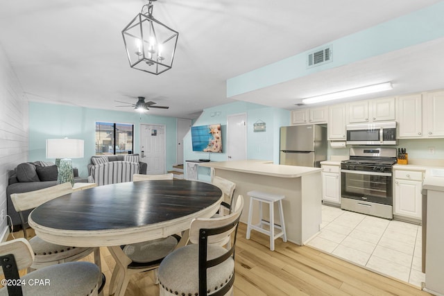 dining room with light hardwood / wood-style flooring and ceiling fan with notable chandelier