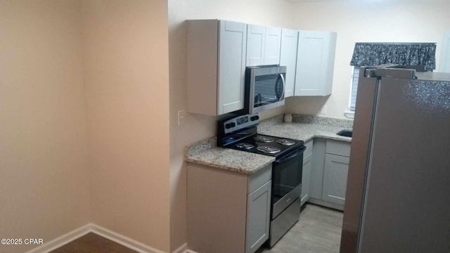 kitchen featuring light hardwood / wood-style flooring, light stone countertops, and appliances with stainless steel finishes