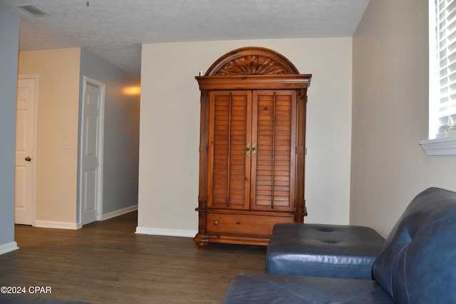 living area featuring a textured ceiling and dark hardwood / wood-style flooring