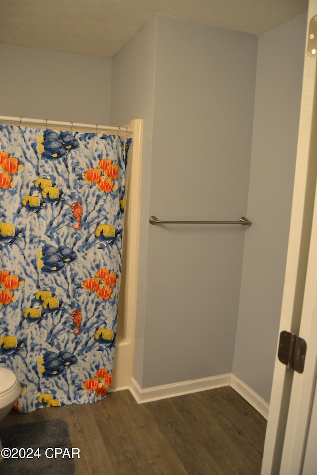 bathroom featuring hardwood / wood-style flooring, a shower with curtain, and toilet