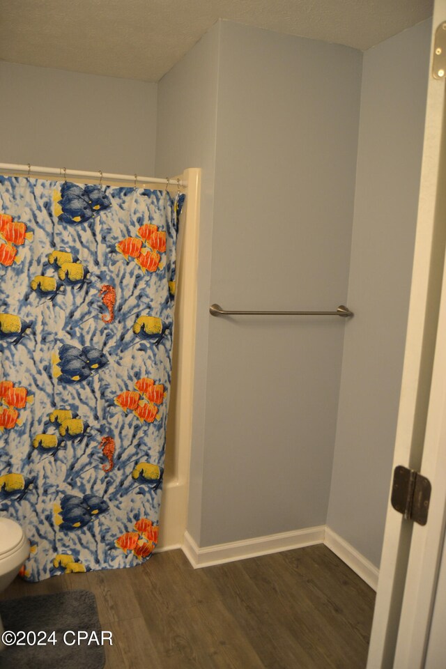 848 Helen Ave, Panama City, FL 32401 - full bathroom with wood finished floors, a shower with shower curtain, toilet, and baseboards