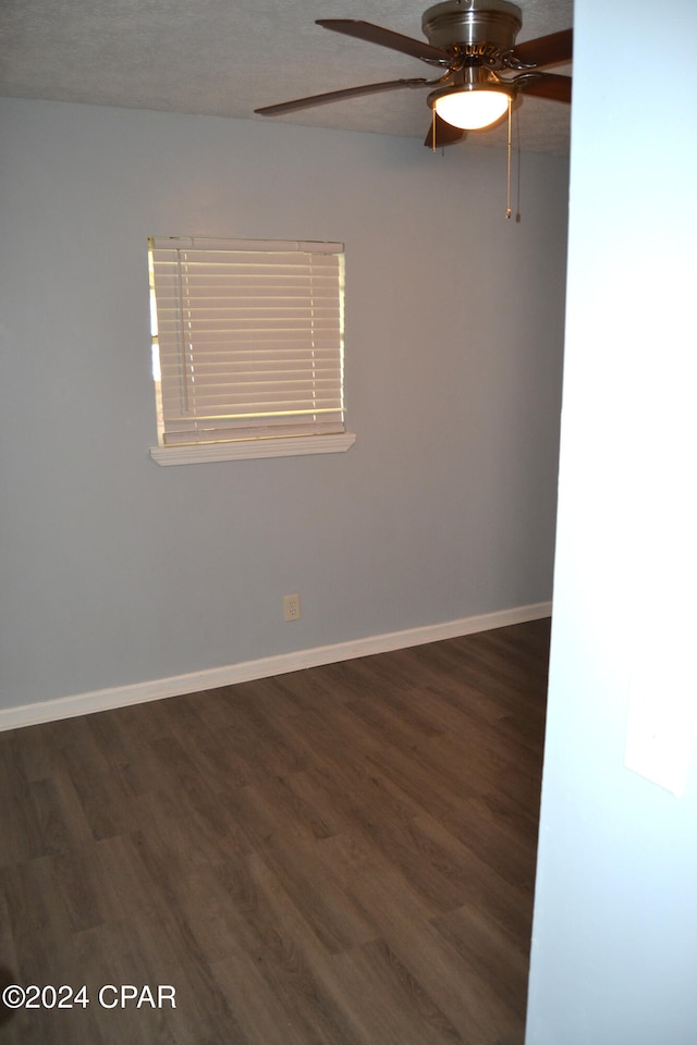 empty room with ceiling fan, dark hardwood / wood-style floors, and a textured ceiling