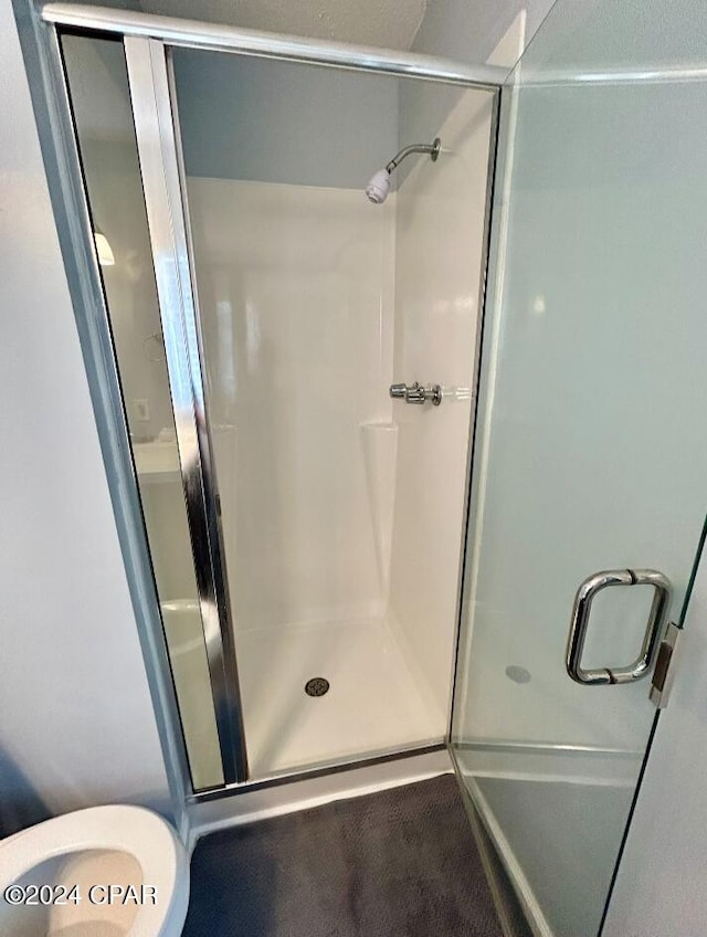 bathroom featuring an enclosed shower and toilet