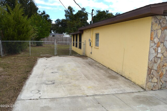 848 Helen Ave, Panama City, FL 32401 - view of side of property with a gate, stone siding, stucco siding, fence, and a patio