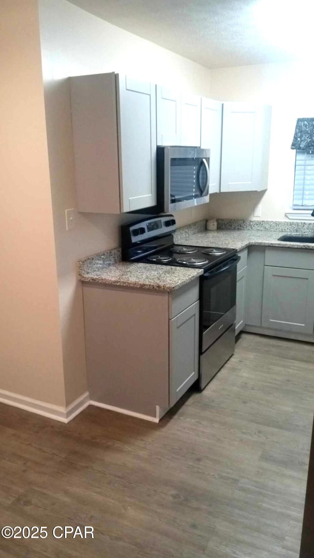 848 Helen Ave, Panama City, FL 32401 - kitchen featuring appliances with stainless steel finishes, a sink, light wood-style flooring, baseboards, and light stone counters