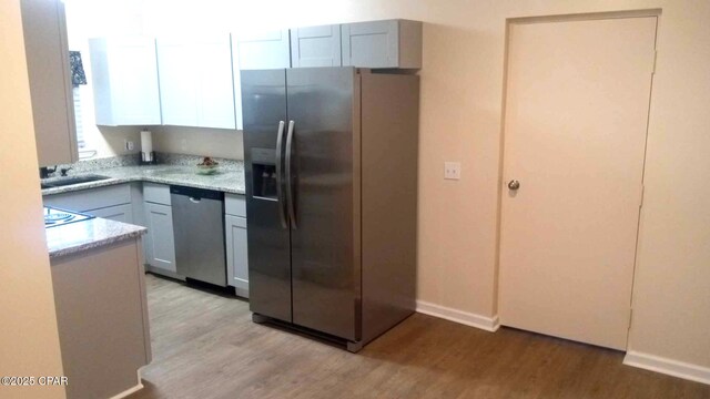 848 Helen Ave, Panama City, FL 32401 - kitchen with appliances with stainless steel finishes, light wood-style floors, a sink, baseboards, and light stone counters